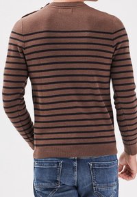 Braun gestreifter Pullover mit navy-blauen horizontalen Linien, gerippter Kragen und Bündchen, mittlere Stricktextur, kombiniert mit blauen Jeans.