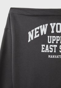 Sweat-shirt gris foncé avec texte blanc "New York Upper East Side Manhattan" sur le devant.