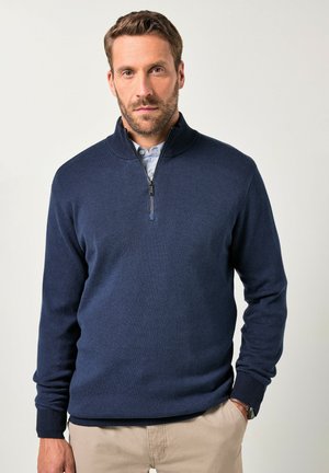 Marineblauwe gebreide trui met een hoge kraag, een halve rits en geribbelde boorden en zoom. Gladde textuur, casual ontwerp dat geschikt is voor het laagjesdragen.