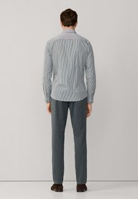 Lange mouwen, gestreepte shirt in blauw en wit, met een button-down kraag en een afgeronde zoom, gecombineerd met grijze broek en bruine schoenen.