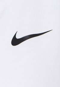 Nike apparel in white fabric featuring a prominent black swoosh logo. Smooth texture, simple design with no additional patterns or accents.