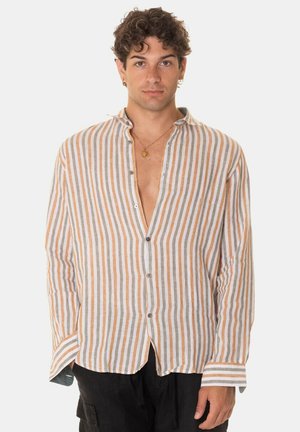 Camicia a maniche lunghe dal taglio morbido, bianca e con righe arancioni, dotata di un'apertura frontale, orlo curvo e texture morbida in lino.