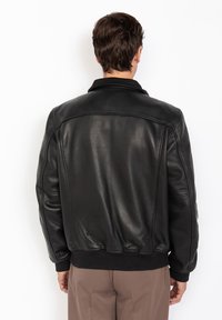 Schwarze Leder-Bomberjacke mit gerippten Bündchen und Saum, die eine glatte Textur und minimale Nähte aufweist. Klassisches Kragenmuster auf der Rückseite.
