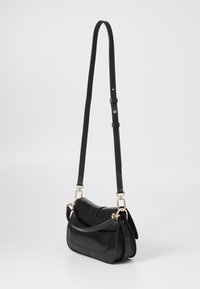 Sac bandoulière en simili cuir noir avec une forme courbe, quincaillerie dorée, sangle réglable et finition brillante. Doté d'une fermeture à rabat sécurisée.