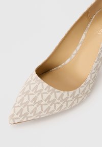 Escarpin beige à talons aiguilles avec un motif géométrique texturé et une doublure intérieure lisse couleur tan sur un fond blanc.