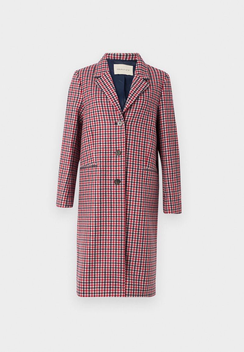 Wzorzysty płaszcz w kolorze czerwonym, białym i niebieskim. Posiada wykładany kołnierz, guziki z przodu i dwie boczne kieszenie. Wykonany z teksturowanej tkaniny.