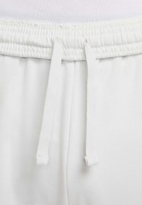 Hvide sweatpants med elastisk talje og snøre, lavet af blødt materiale, der viser en glat tekstur og minimal detaljering.