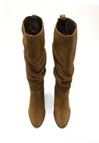 Stivali alti in suede marrone con un design morbido e una texture liscia; foderatura nera visibile nella parte superiore. Suole piatte con punte arrotondate.