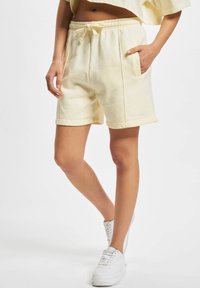 Lys gule bomullshorts med elastisk midje og snor. Har sidelommer og en liten logo detalj i kanten.