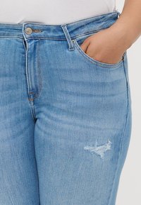 Light blue denim jeans with a classic cut. Features a front pocket, subtle distressing on the thigh, and contrast stitching.