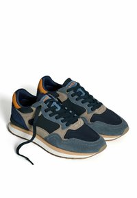 Blaue und beigen Wildledersneaker mit schwarzen Schnürsenkeln, orangefarbenen Akzenten an der Ferse und weißen Sohlen mit Gummiböden, einer Schnürsenkel offen.