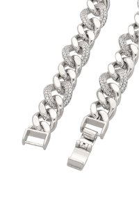 Stříbrný kovový náramek z řetězu s vzájemně provázanými články. Vyznačuje se hladkými plochami a akcenty z průhledných kamenů. Zapínání viditelné na jednom konci.