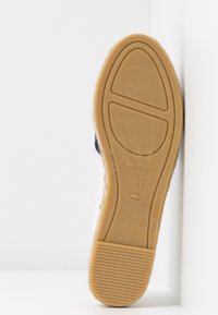 Chaussure espadrille avec une semelle en jute naturel, une tige en toile blanche et des détails en caoutchouc. Taille 37, marquée "Fabriqué en Espagne" sur la semelle.