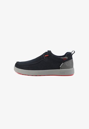 Marineblauwe suède schoenen met een grijze rubberen zool en rode accenten. Beschikt over een lage profiel, minimale stiksel en een trektab aan de hiel.