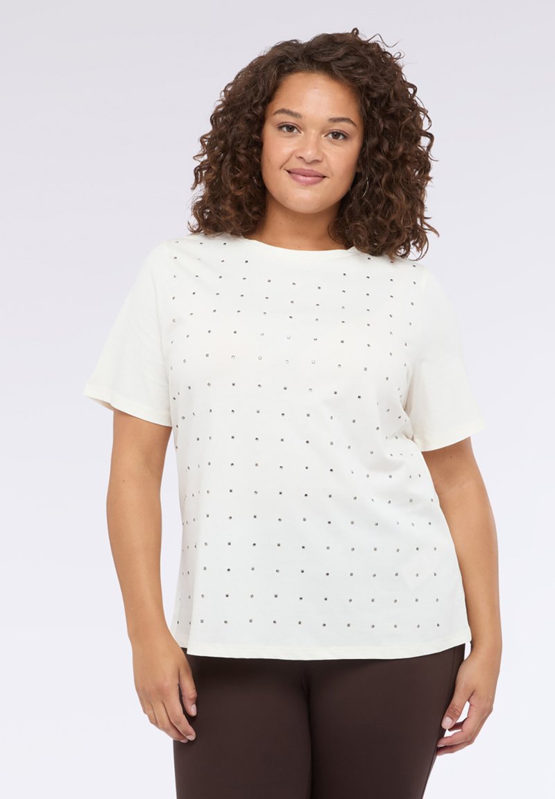 Camiseta blanca de manga corta y escote redondo, que presenta un patrón de cuadrícula de pequeños clavos plateados en la parte delantera.