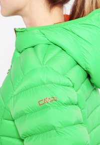 Zielona kurtka puchowa z pikowaną teksturą, wyposażona w wysoki kołnierz i widoczne czerwone logo CMP na rękawie. Lekki materiał.