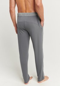 Grijze joggerbroeken gemaakt van zachte, rekbare stof. Beschikt over een brede elastische tailleband en zijzakken. Glad materiaal met een ontspannen pasvorm.