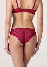 Set di lingerie in pizzo bordeaux con motivi floreali, bordi ondulati e spalline regolabili. Tessuto morbido e trasparente con un taglio classico.