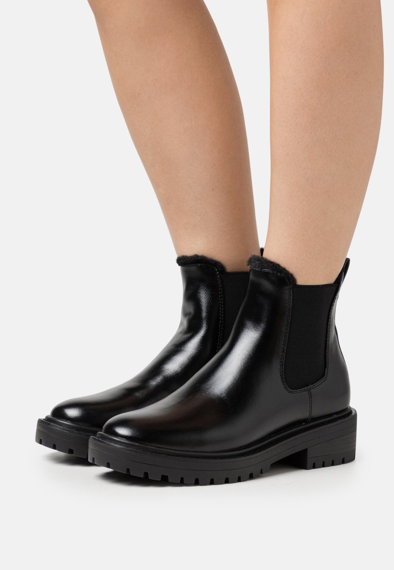 Bottes chelsea en cuir noir avec des panneaux élastiques latéraux, doublure intérieure texturée et semelles robustes pour une bonne adhérence. Fini lisse et bout rond.