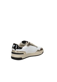 Sneaker bianca con dettagli dorati, tallone nero lucido e suola texturizzata. Caratterizzata da un design con lacci e cuciture sui lati.