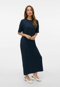 Mörkblå, knälång klänning i mjukt material med korta ärmar och avslappnad passform. Tillsammans med vita högklackade skor med slingback-design.