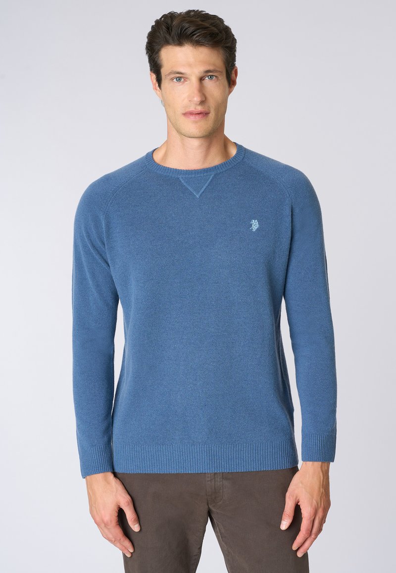 Maglione azzurro chiaro a girocollo con maniche lunghe, realizzato in materiale morbido. Presenta polsini e fondo a costine, con un piccolo logo sul petto.