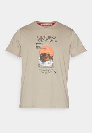 T-shirt en coton beige clair avec un graphisme NASA, un cercle orange et un design de globe. Le texte noir indique "Administration nationale de l'aéronautique et de l'espace."