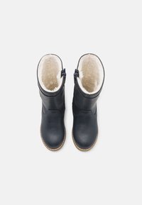 Bottes en cuir bleu marine avec doublure en fausse fourrure, présentant une texture lisse, un bout rond et des fermetures éclair latérales pour un accès facile.