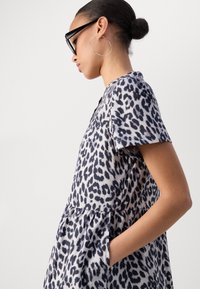 Šaty s leopardím potlačou v šedej a čiernej farbe, krátke rukávy, zúžený pás s vreckami, vyrobené z ľahkej textílie, hladká textúra.