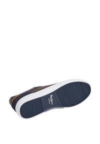 Tengerészkék sportcipő fehér gumitalppal, texturált tapadómintával, barna díszítésekkel és oldalsó márkajelzéssel.