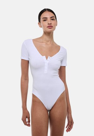 Bodysuit blanc à côtes avec manches courtes, décolleté en V et détails de boutons à l'avant. Texture lisse, coupe ajustée.