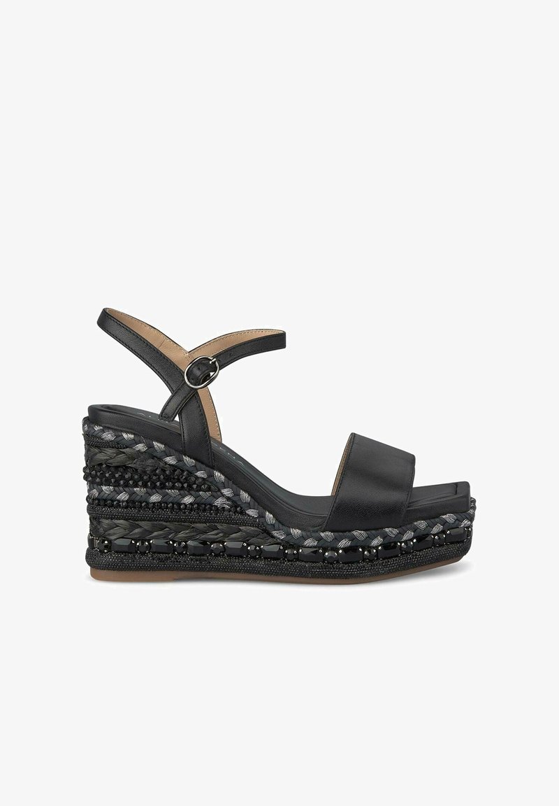 Schwarze Keilsandaletten mit einem glatten Lederoberteil, verstellbarem Knöchelriemen und einer strukturierten, geflochteten Plattform, die kontrastierende Materialien und Perlenverzierungen aufweist.