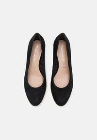 Scarpe court nere in suede con punta arrotondata e lati aperti. L'interno presenta una fodera beige e un logo discreto sulla soletta. Taglia 37.
