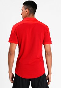 Rød polo t-shirt med korte ærmer, krave og en buet kant. Fremstillet af et glat, vævet stof. Funktioner solid rød farve med sømløse skulderdetaljer.