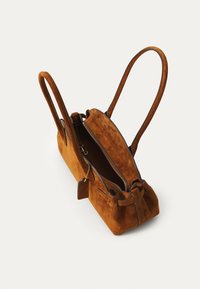 Borsa in suede marrone con doppio manico, zip sulla parte superiore e fodera interna. Presenta una forma semplice e rotondeggiante e un piccolo tag in pelle come accentuazione.
