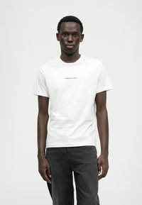 T-shirt de algodão branca com decote redondo e mangas curtas, com "REPLAY" impresso em uma fonte moderna e ousada no peito.