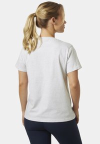 Camiseta de algodón blanca con mangas cortas, un escote redondeado y un ajuste ligeramente holgado. La tela parece suave con una textura mínima.