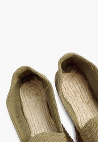 Groene espadrilles met een geweven stofexterieur, platte touwzolen en een gestructureerde binnenzool. Open ontwerp met zachte randen en minimale stiksels.
