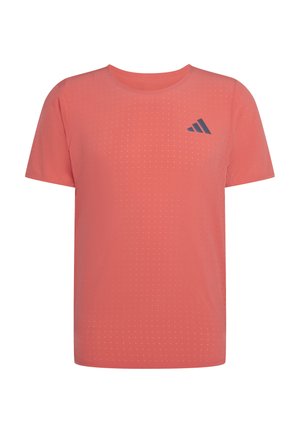 Koralowa, sportowa koszulka z krótkim rękawem, z małym wzorem kropek i ciemnoszarym logo Adidas na lewej piersi.