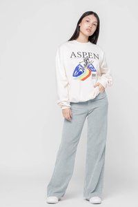 Sudadera crema con gráfico de "ASPEN", combinada con pantalones de pana anchos en azul claro. Zapatillas blancas completan el conjunto.