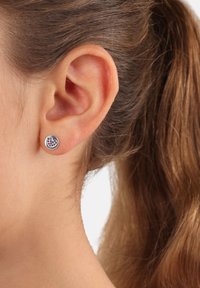Pendientes de botón de plata redondos con un diseño de corazón rosa, que presentan pequeñas piedras preciosas dispuestas en forma de corazón sobre un fondo metálico.