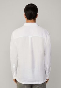 Weißes Leinenhemd mit langen Ärmeln, klassischem Kragen und Knopfmanschetten, gerader Schnitt und glatter Textur. Einfaches und minimalistisches Design.