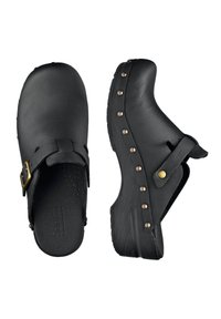 Zoccoli in pelle nera con punta arrotondata, cinturino regolabile e borchie decorative in metallo lungo il lato. Interno testurizzato e suola antiscivolo.