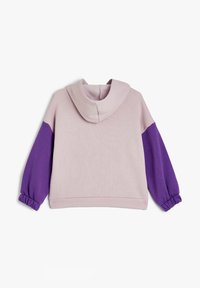 Felpa con cappuccio di colore rosa con maniche viola, dotata di polsini elasticizzati e un tessuto morbido e testurizzato.