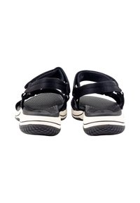 Sandalias negras con correas ajustables, plantilla texturizada y suela blanca en contraste. Parte trasera redondeada, suela de goma duradera con patrón de tracción.