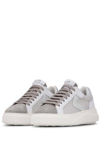 Baskets blanches et grises avec un bout en daim, des panneaux latéraux en mesh et des semelles en caoutchouc texturé. Elles présentent des lacets ronds et une étiquette de langue de marque.