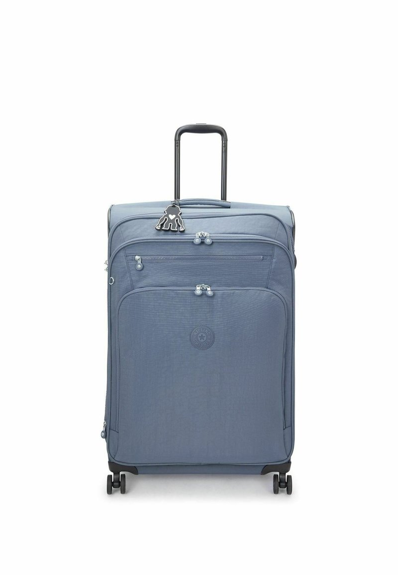 Valise en tissu bleu avec une surface texturée, deux compartiments zippés, quatre roues et une poignée rétractable noire. Comprend un accent porte-clés.