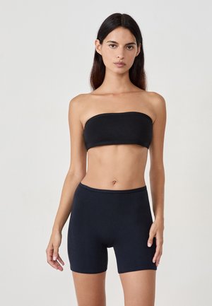 Haut noir sans bretelles et short taille haute en tissu lisse et extensible. Les vêtements n'ont pas de motifs ni de matériel visible.