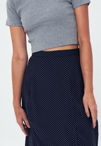 Grå randig croppad topp som matchas med en marinblå kjol med vita prickar. Kjolen har sidofickor och en avslappnad passform.