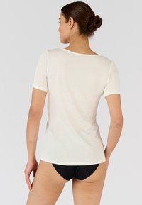 T-shirt a maniche corte in morbido e leggero tessuto bianco con scollatura rotonda e una forma leggermente aderente, caratterizzato da una texture liscia.